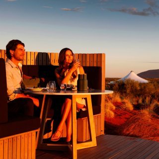 Couple enjoying a sunset drink with views of Uluru at Longitude 131. Photo: Longitude 131